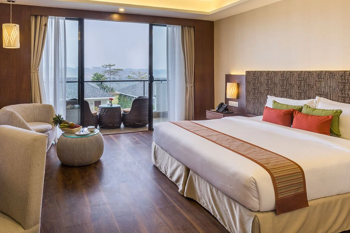 A spacious resort room with a panoramic window onto the peaks